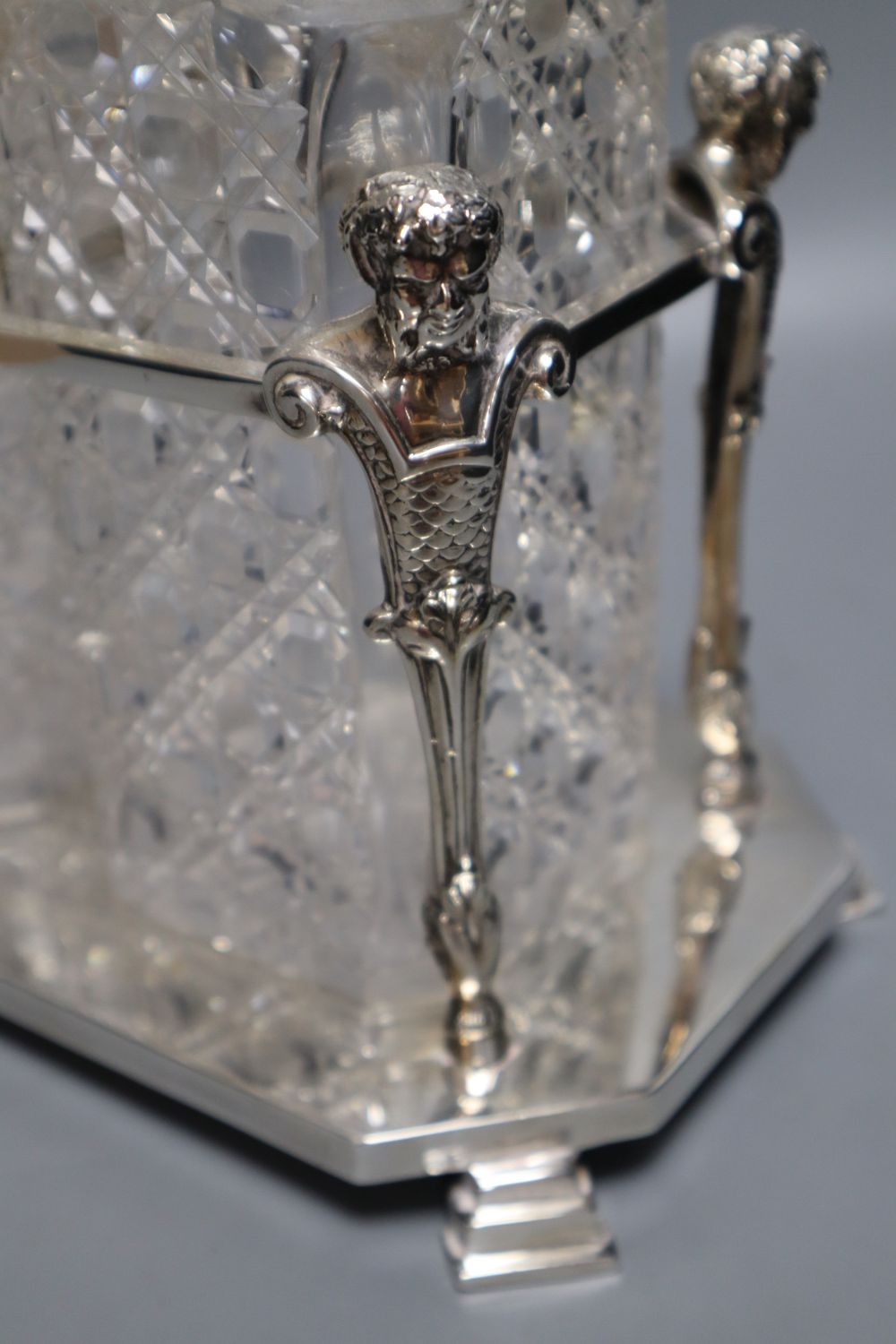 An Edwardian plated decanter stand, fitted three square cut glass decanters and three silver bottle labels, 36cm wide